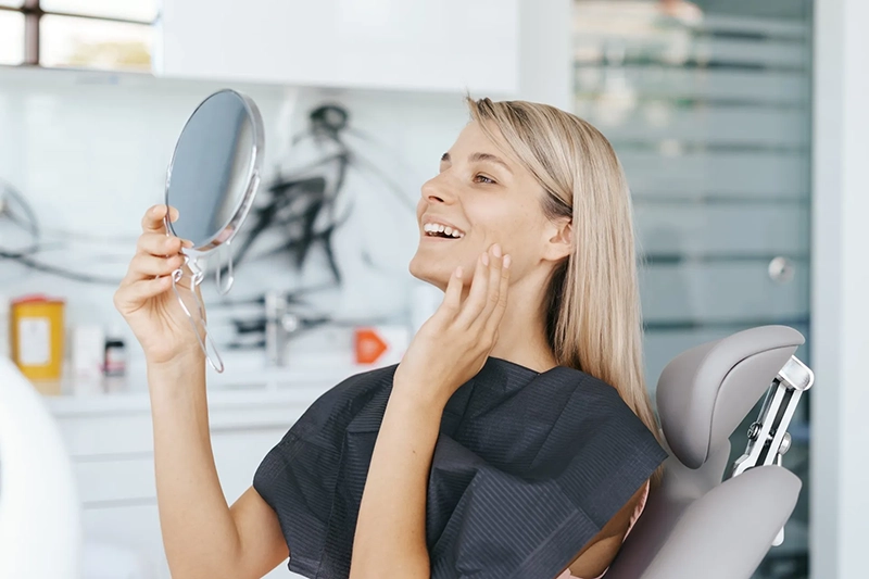 Patient looking to her smile in the mirror after treatment